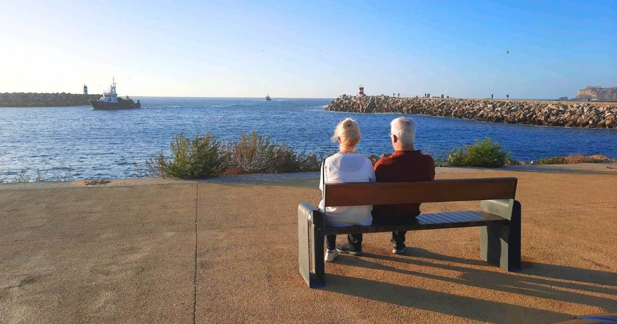 Couple sitting on a bench overlooking the marina and ocean in Nazaré Portugal